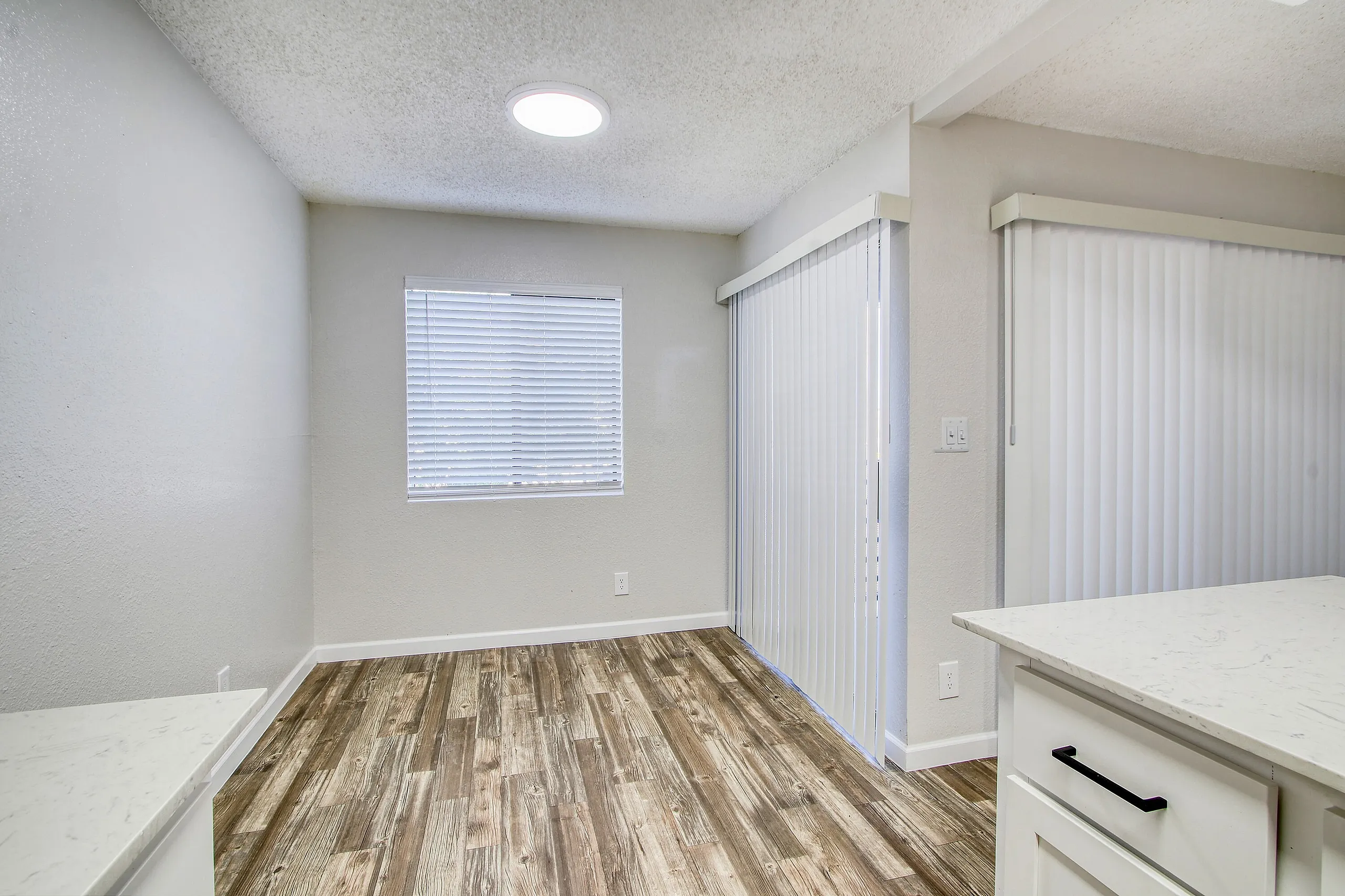 Bedroom, wood-style plank flooring, recessed lighting, vertical blinds, white cabinetry