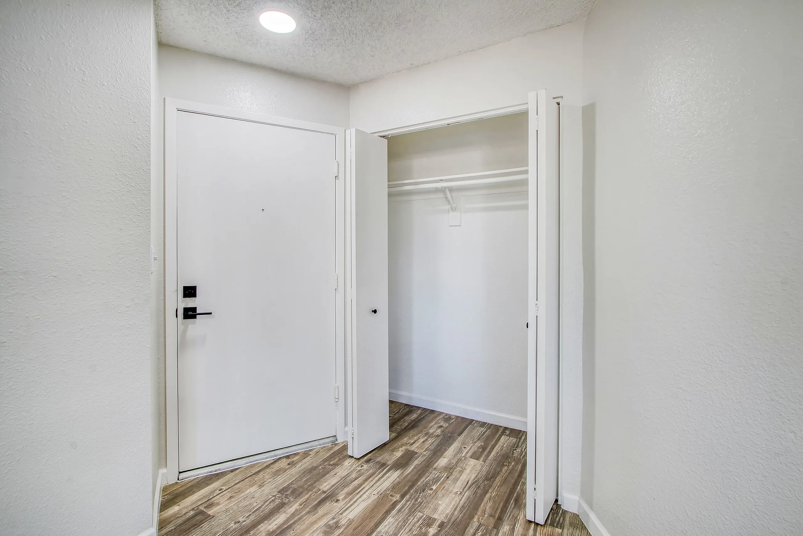 Bedroom entry, open closet with hanging rod, wood-style plank flooring, white walls
