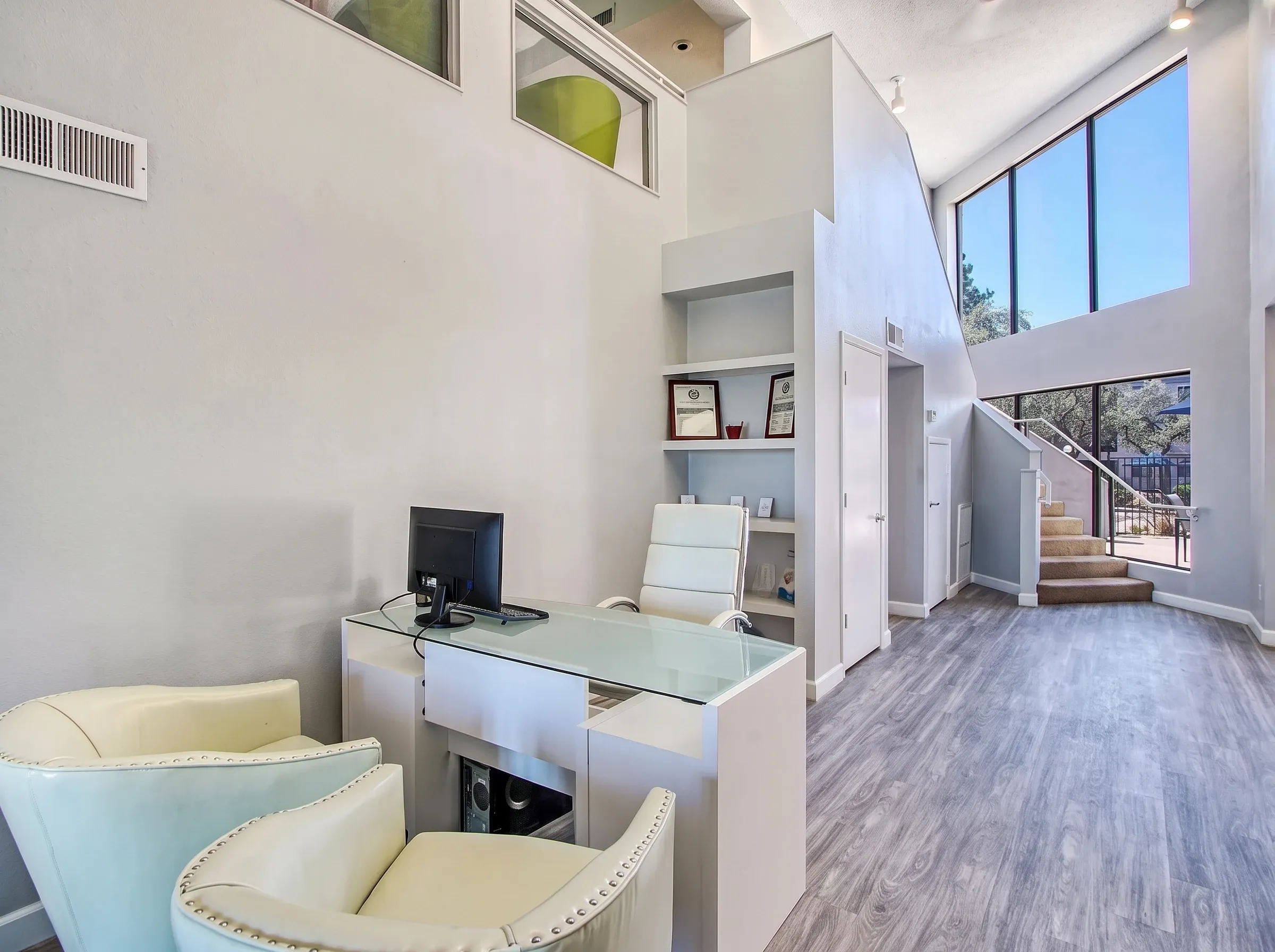 Loft workspace, glass desk, wood-style plank flooring, high ceilings, staircase