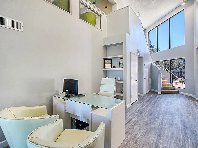 Loft workspace, glass desk, wood-style plank flooring, high ceilings, staircase