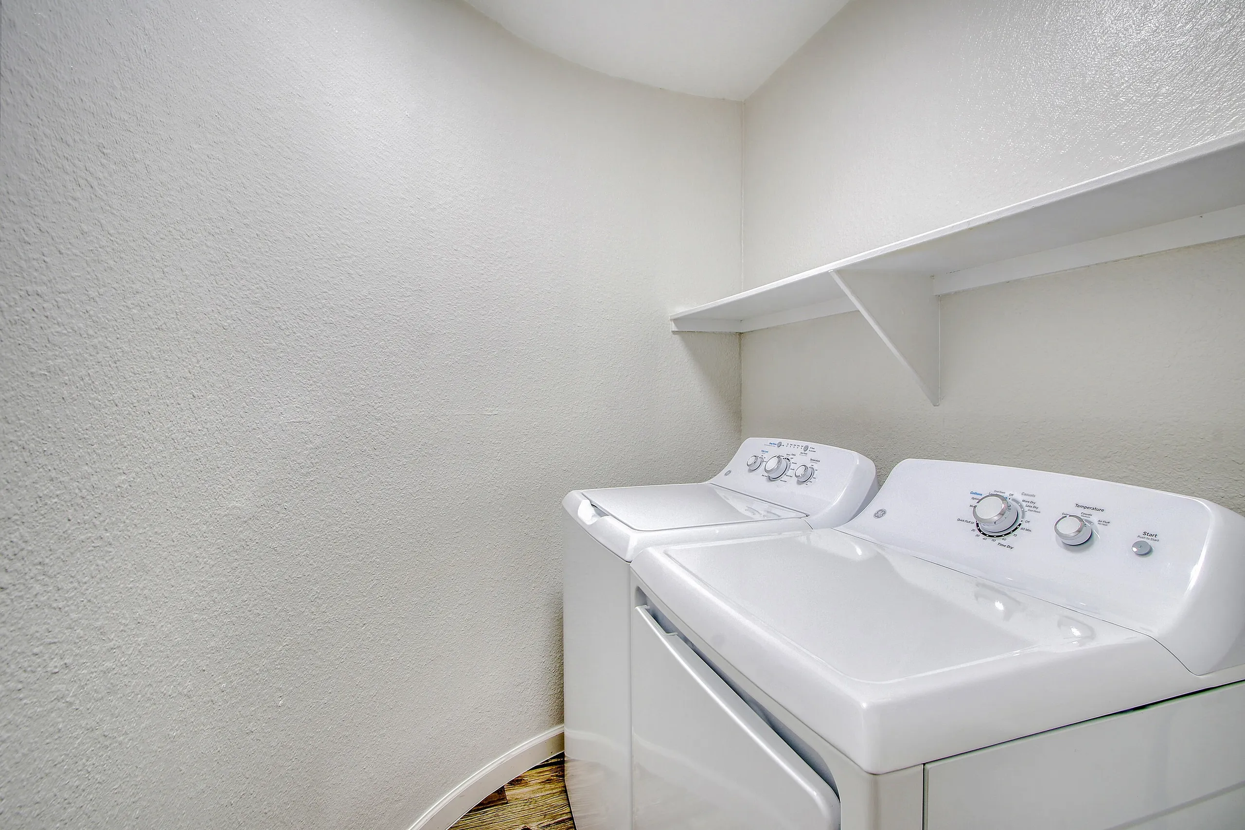 Laundry room, white washer and dryer, wall shelf, wood-style plank flooring