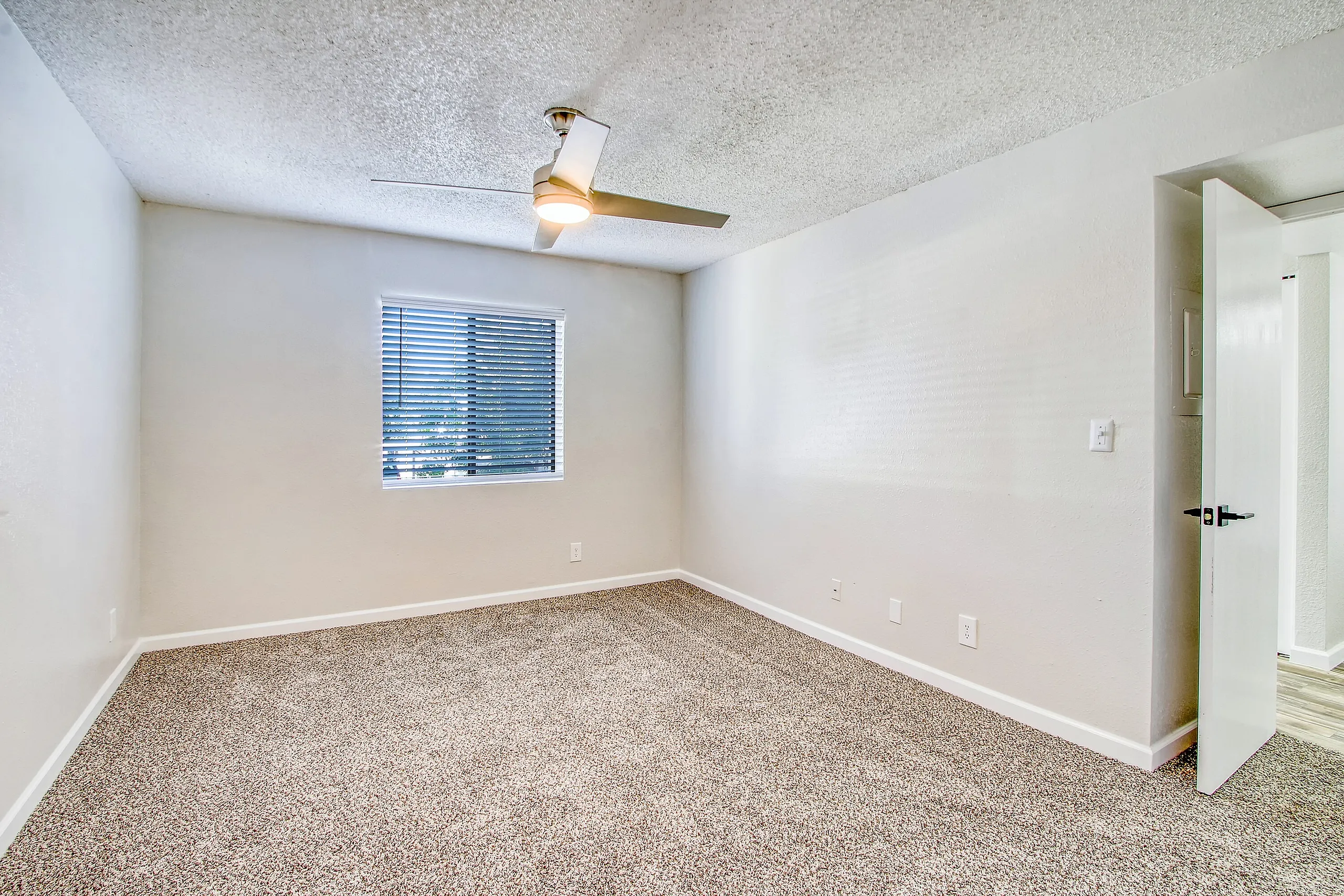 Bedroom, beige carpet flooring, ceiling fan with brass finish, window with blinds, white walls