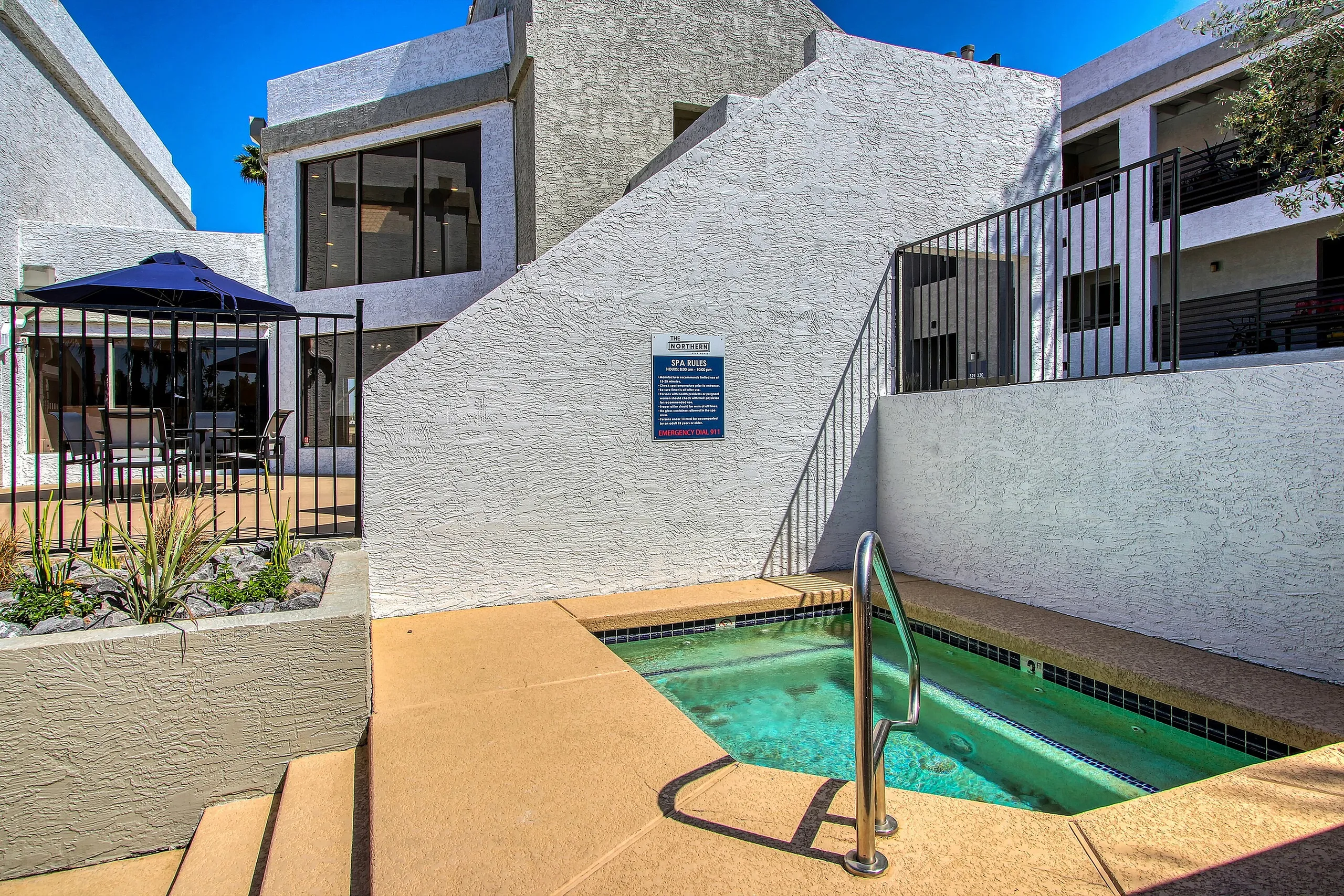 Pool area, geometric concrete deck, bright turquoise water, metal ladder, modern architectural setting