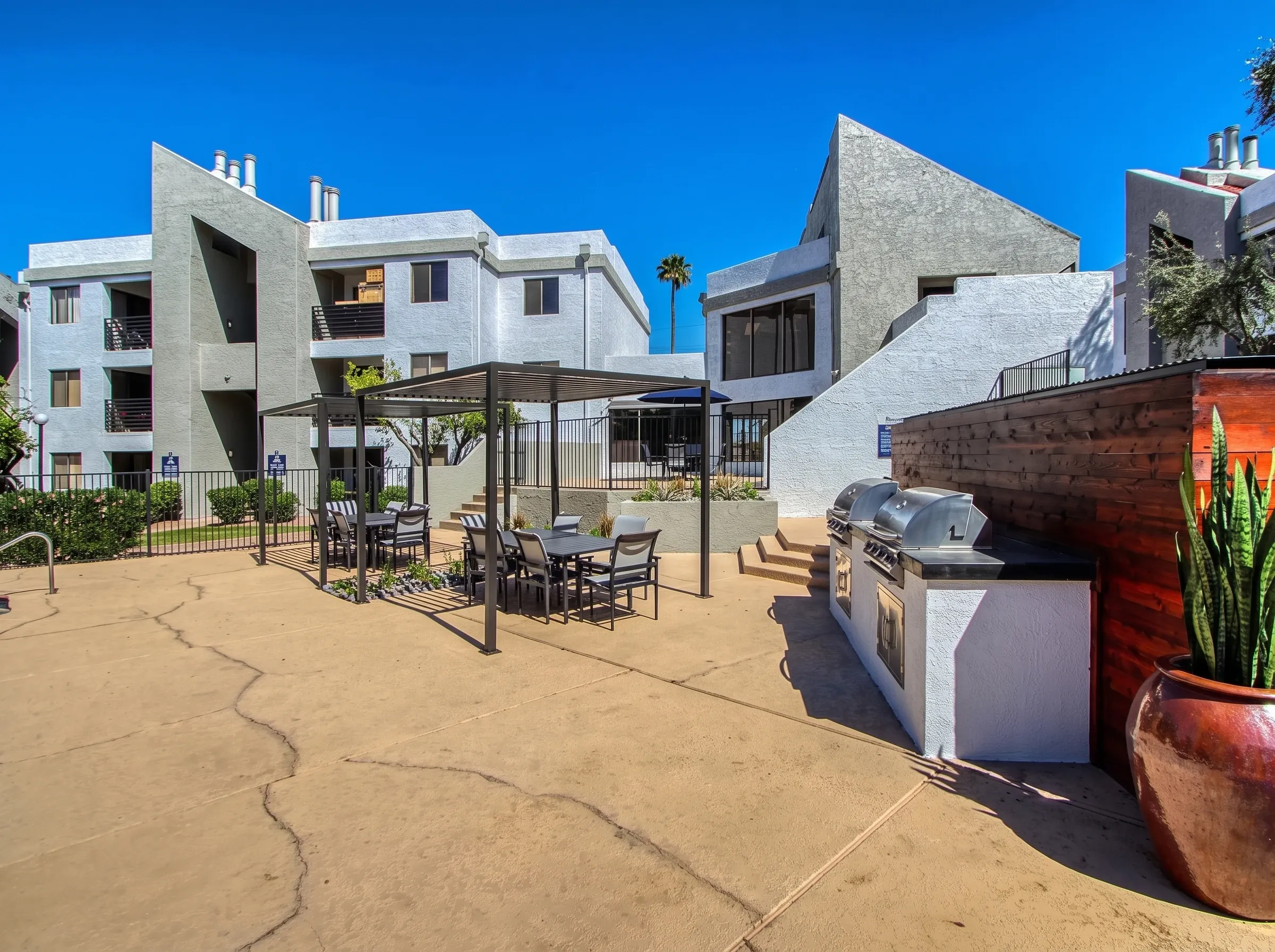 Outdoor courtyard with patio seating, built-in grill, concrete decking, multi-story residential buildings