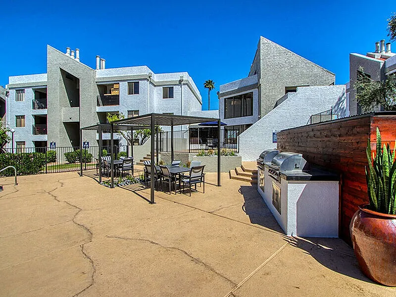 Outdoor courtyard with patio seating, built-in grill, concrete decking, multi-story residential buildings