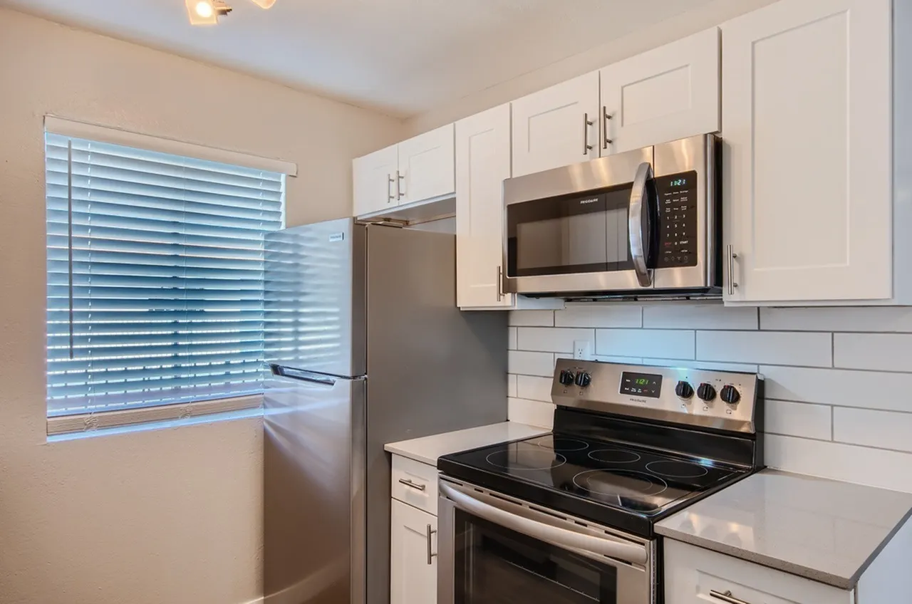Kitchen, white shaker cabinetry, stainless steel appliances, white subway tile backsplash, black cooktop