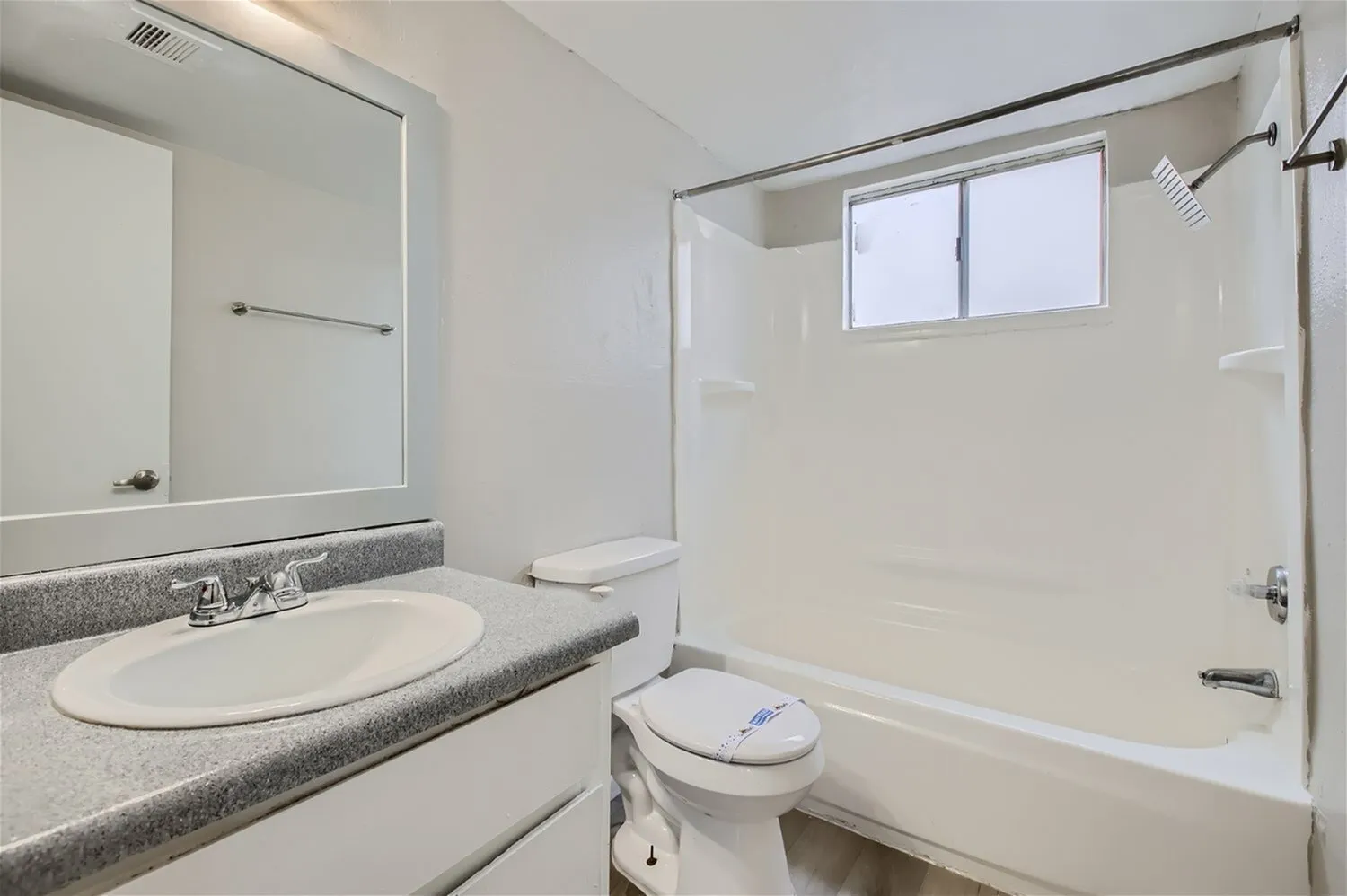 Bathroom, round white sink, gray countertop, large mirror, glass shower enclosure