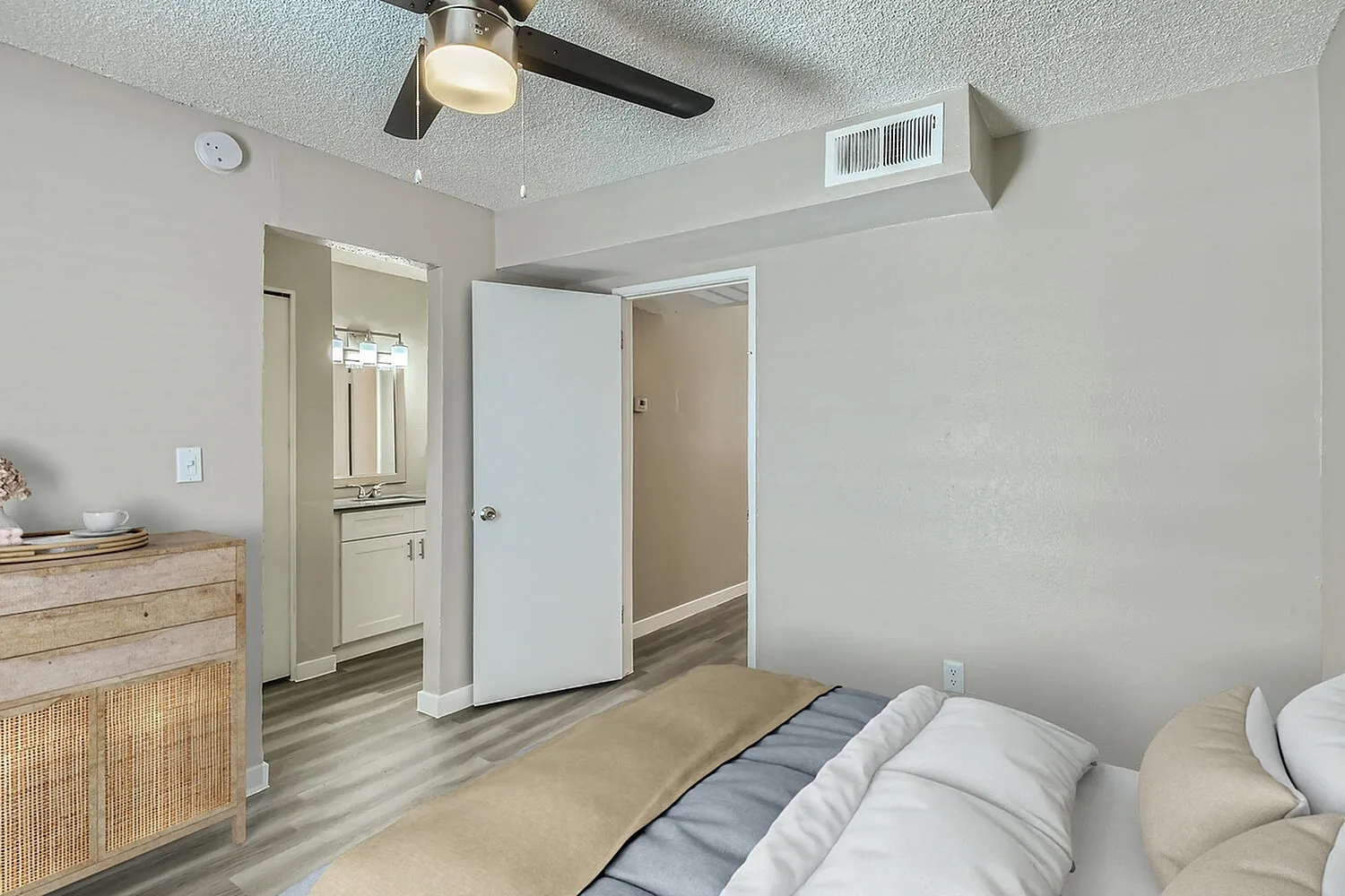 Primary bedroom, wood-style plank flooring, ceiling fan, ensuite bathroom with vanity