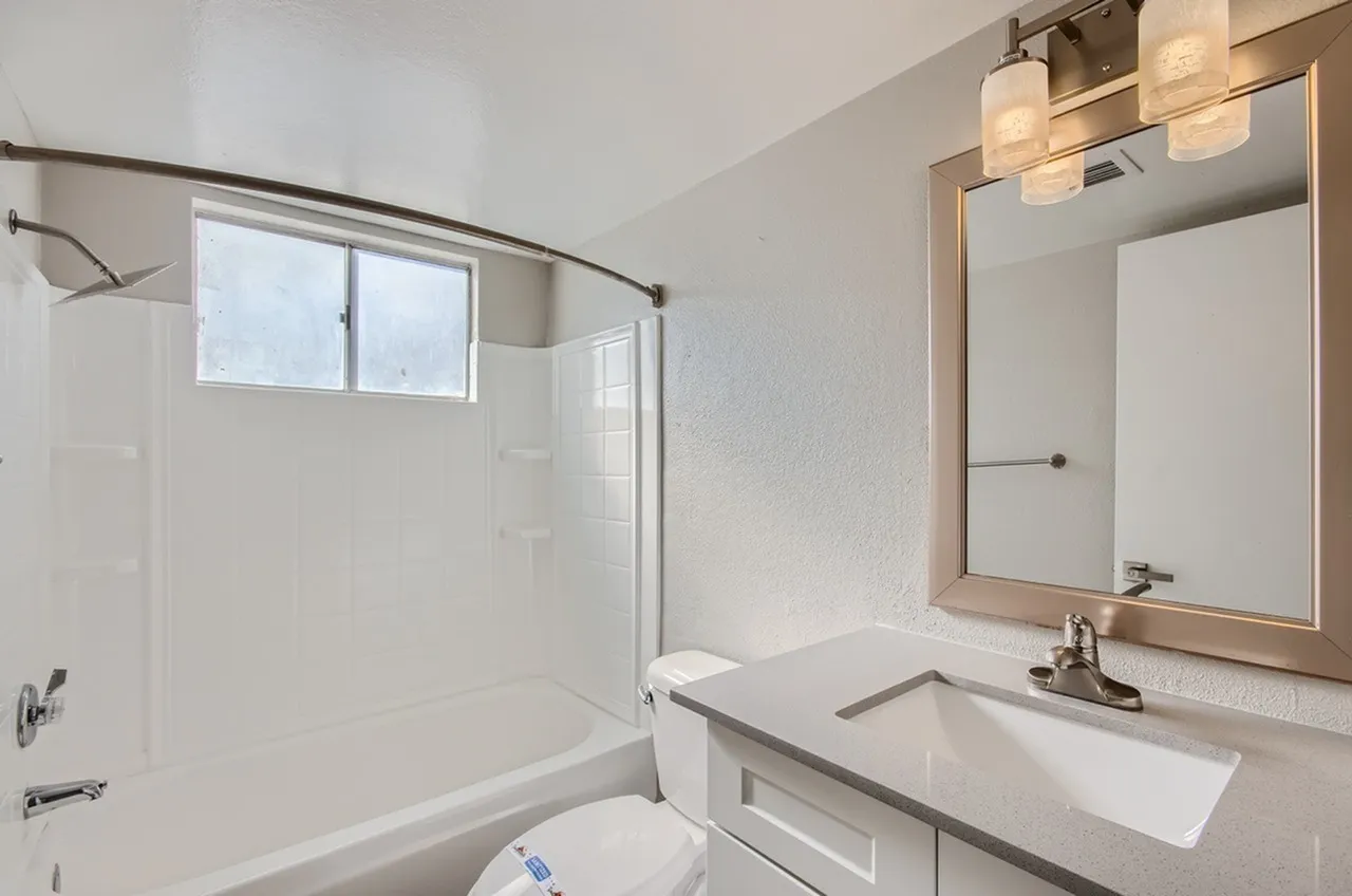 Bathroom, white subway tile shower surround, quartz countertops, framed mirror, chrome fixtures