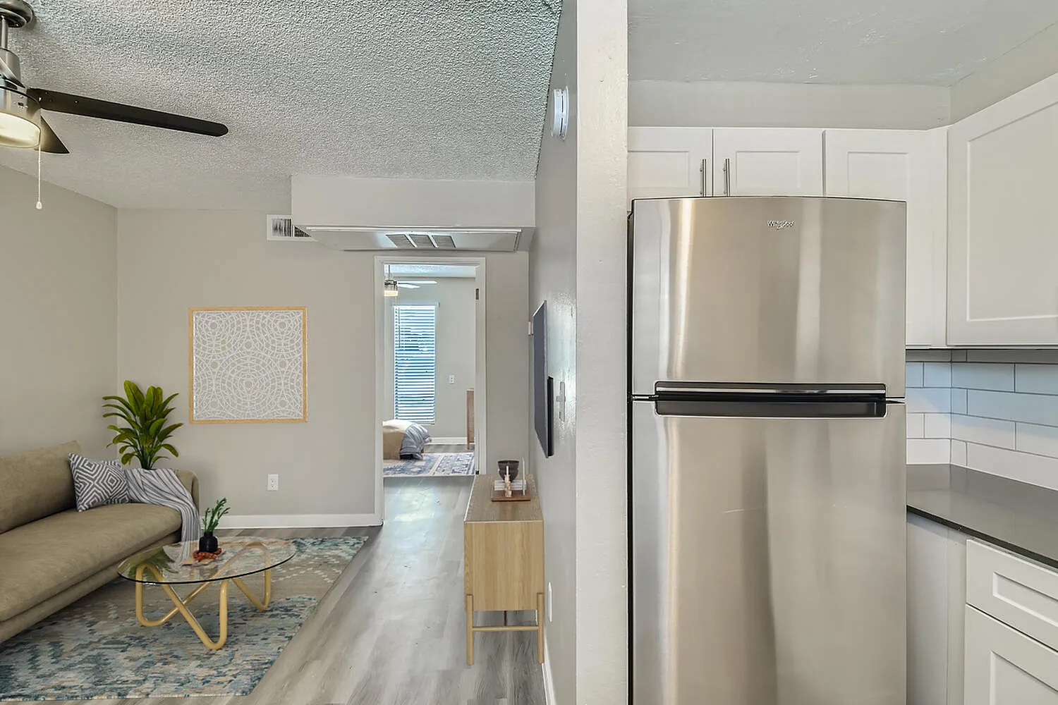 Kitchen and living room, white shaker cabinetry, stainless appliances, wood-style plank flooring, ceiling fan