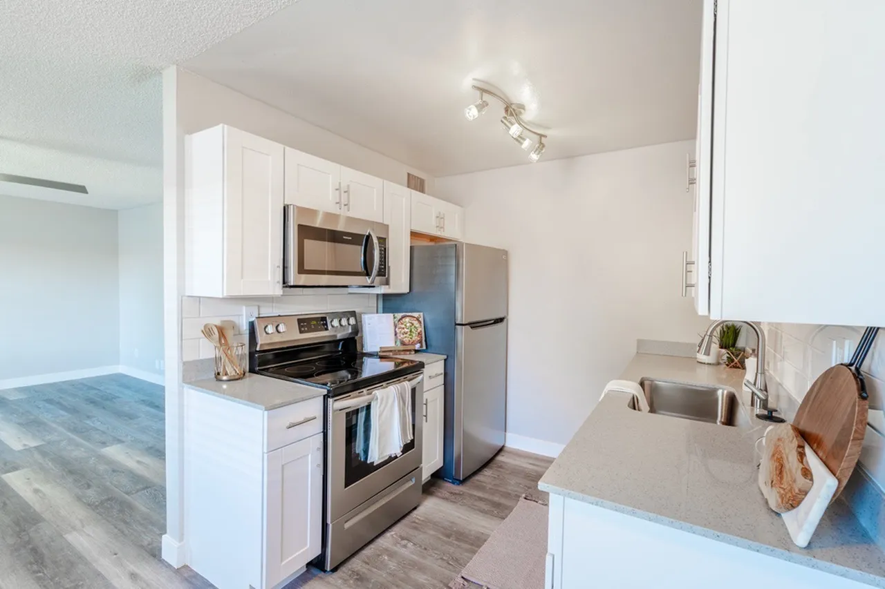 Kitchen, white shaker cabinetry, stainless appliances, quartz countertops, wood-style plank flooring