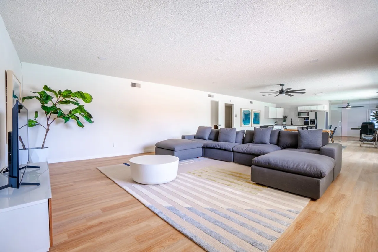 Living room, gray sectional sofa, wood-style plank flooring, striped area rug, ceiling fan