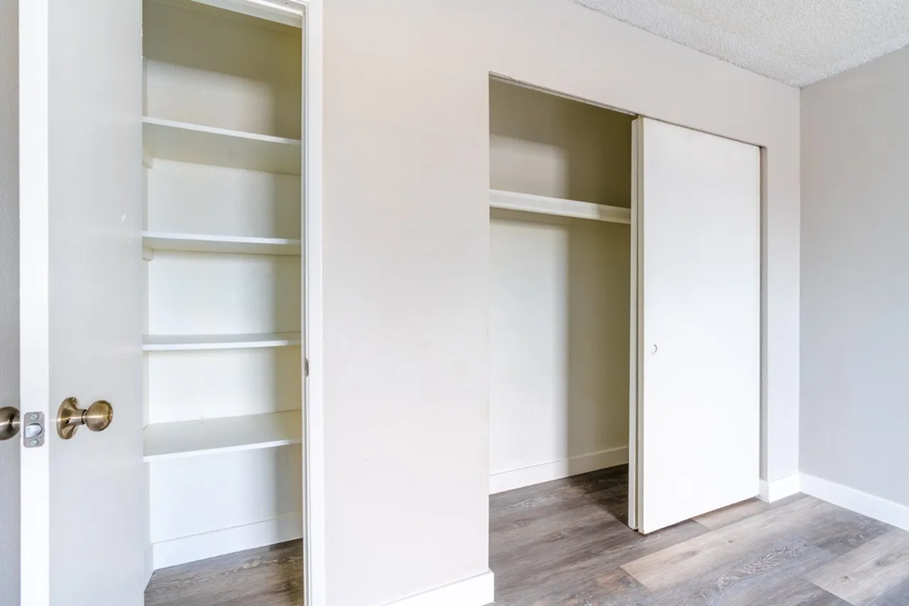 Bedroom closet with sliding glass doors, built-in shelving, wood-style plank flooring