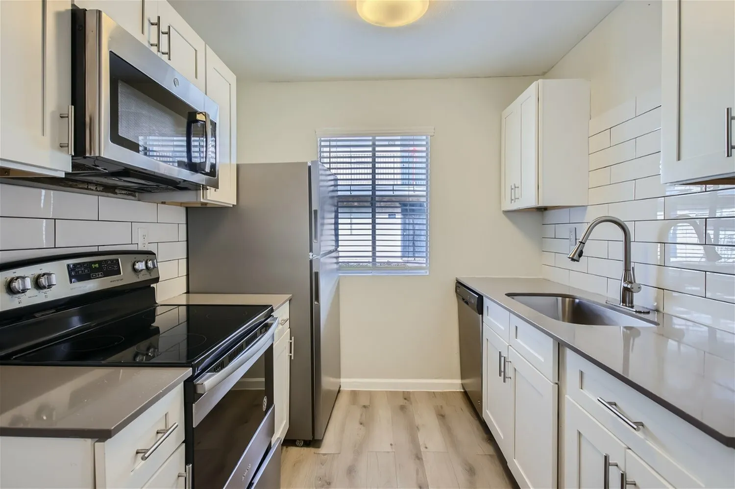 Kitchen, white shaker cabinetry, subway tile backsplash, stainless appliances, wood-style plank flooring
