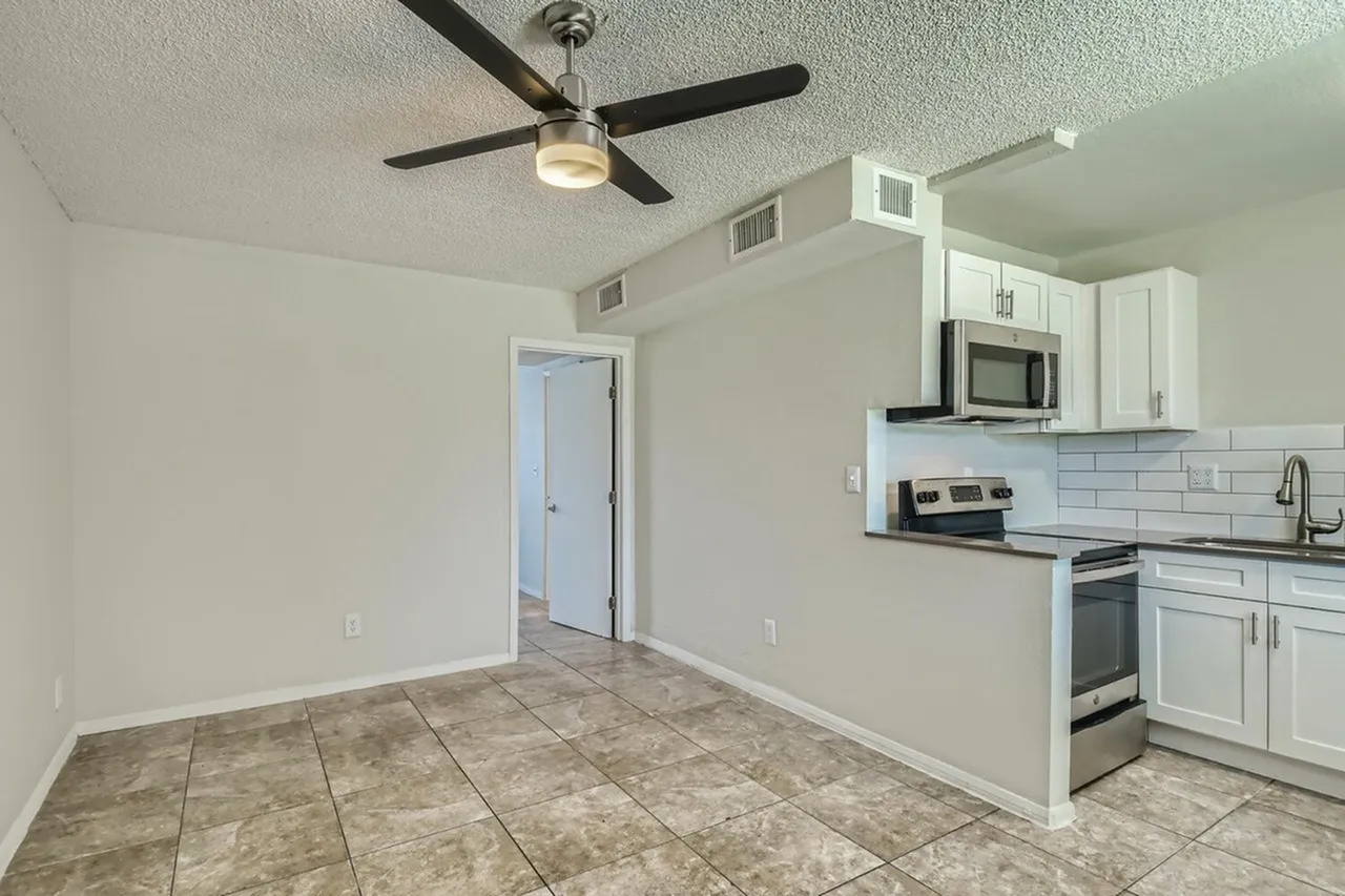 Kitchen and dining area, white shaker cabinetry, stainless appliances, subway tile backsplash, wood-style plank flooring, ceiling fan