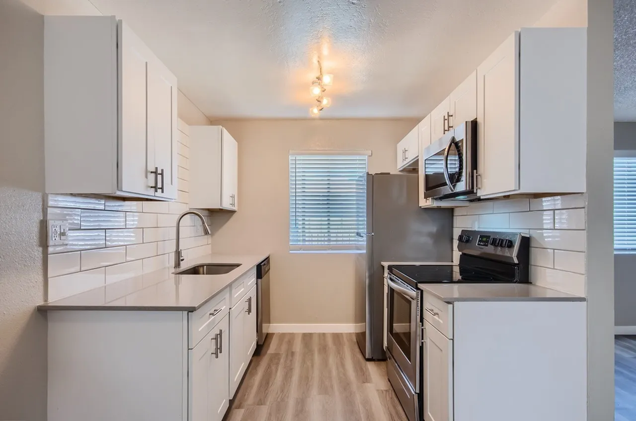 Kitchen, white shaker cabinetry, quartz countertops, stainless appliances, wood-style plank flooring