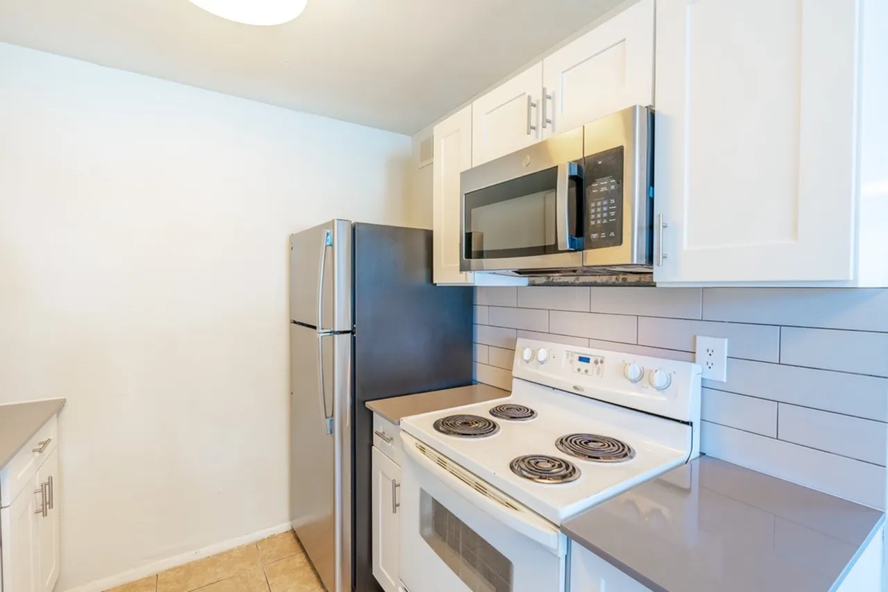 Kitchen, white cabinetry, stainless steel microwave, white coil stovetop, wood-style plank flooring