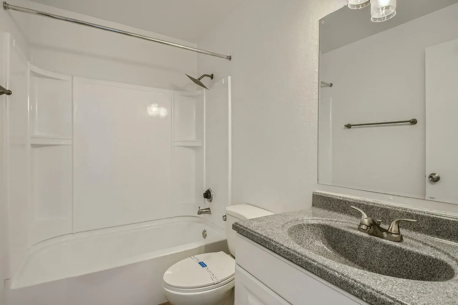 Bathroom, gray granite countertop, single vanity sink, white shaker cabinetry, tub with glass enclosure