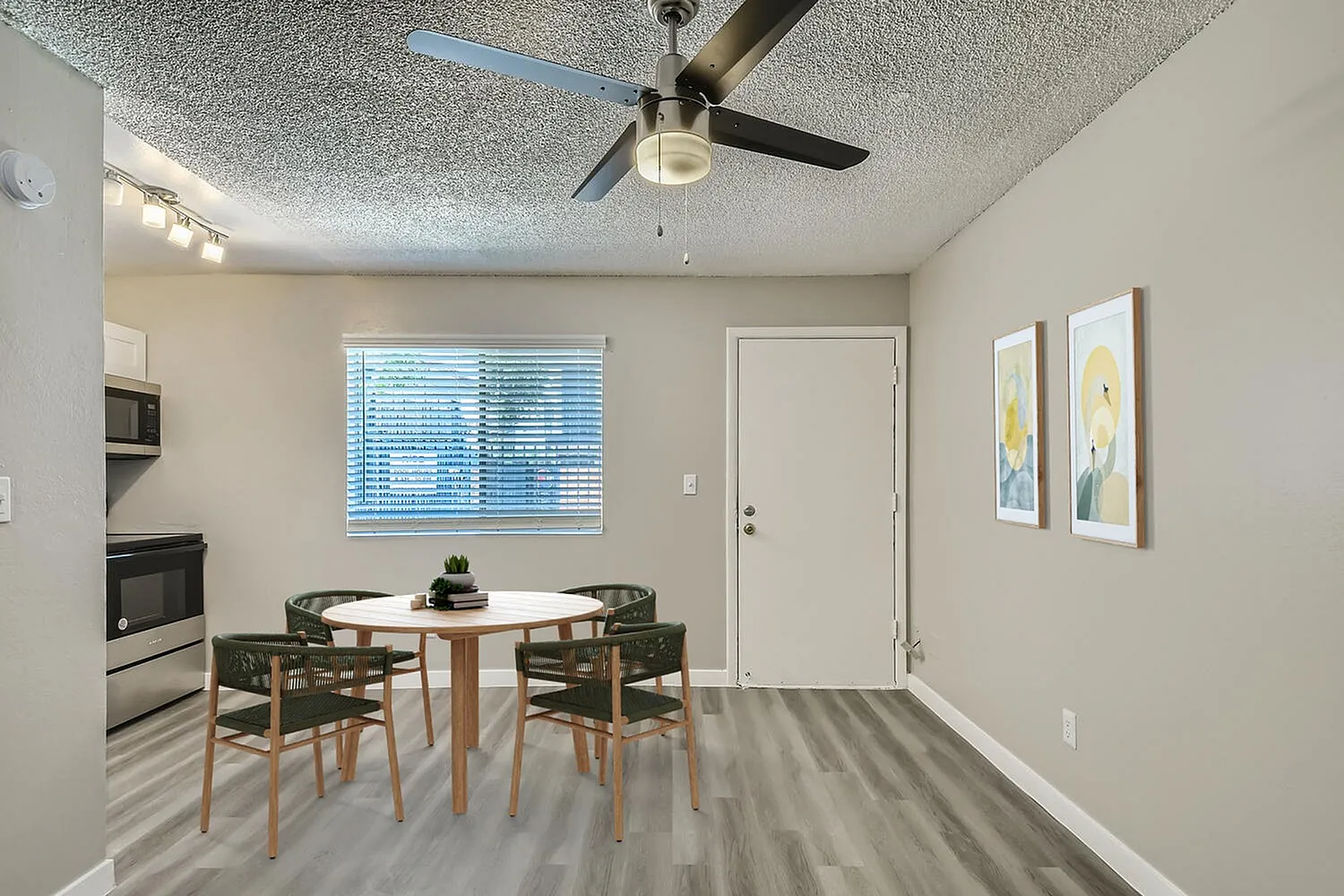 Dining area, wood-style plank flooring, round table with chairs, ceiling fan, stainless appliances visible