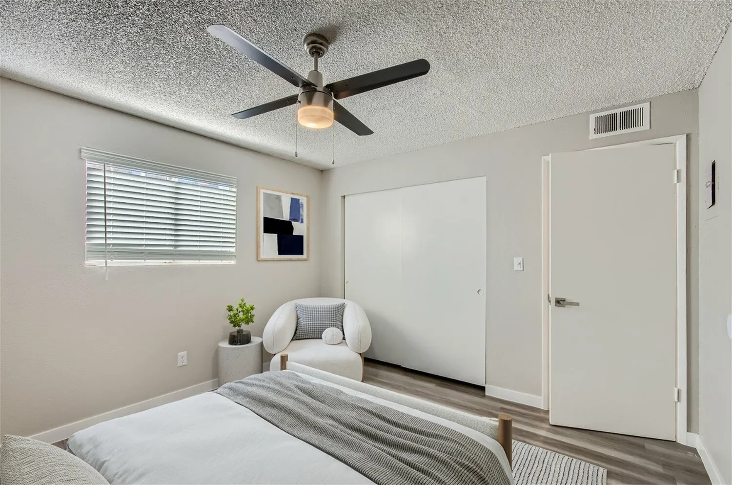 Primary bedroom, wood-style plank flooring, ceiling fan with light fixture, blinds on window