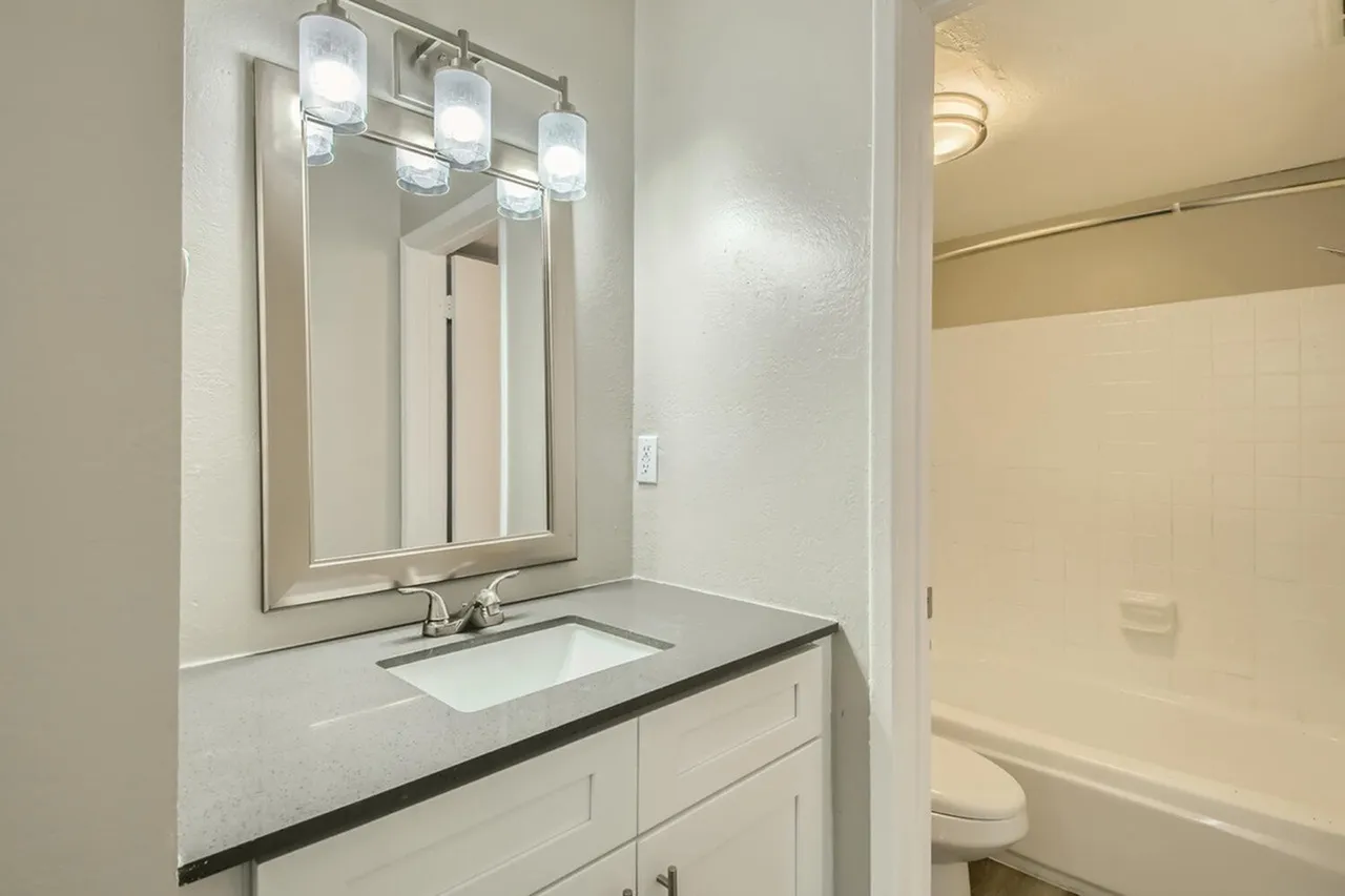 Bathroom, white cabinetry, quartz countertop, framed mirror with sconces