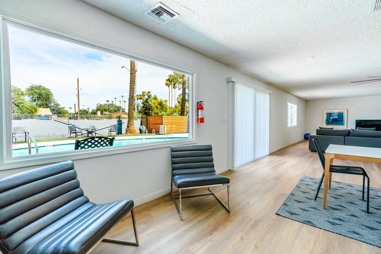 Lounge area, striped accent chairs, wood-style plank flooring, large windows with courtyard view