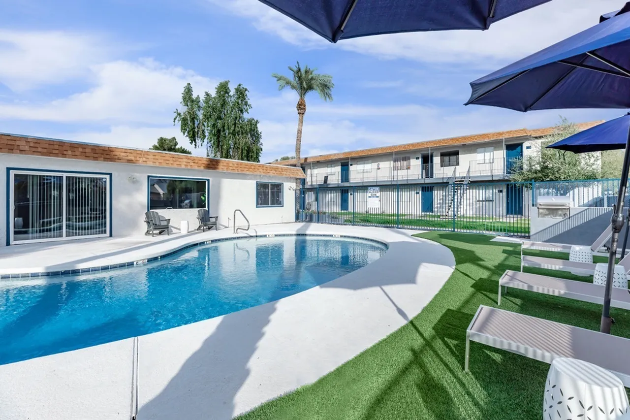 Resort-style pool, white decking, lounge chairs, blue umbrellas, palm tree, Glendale