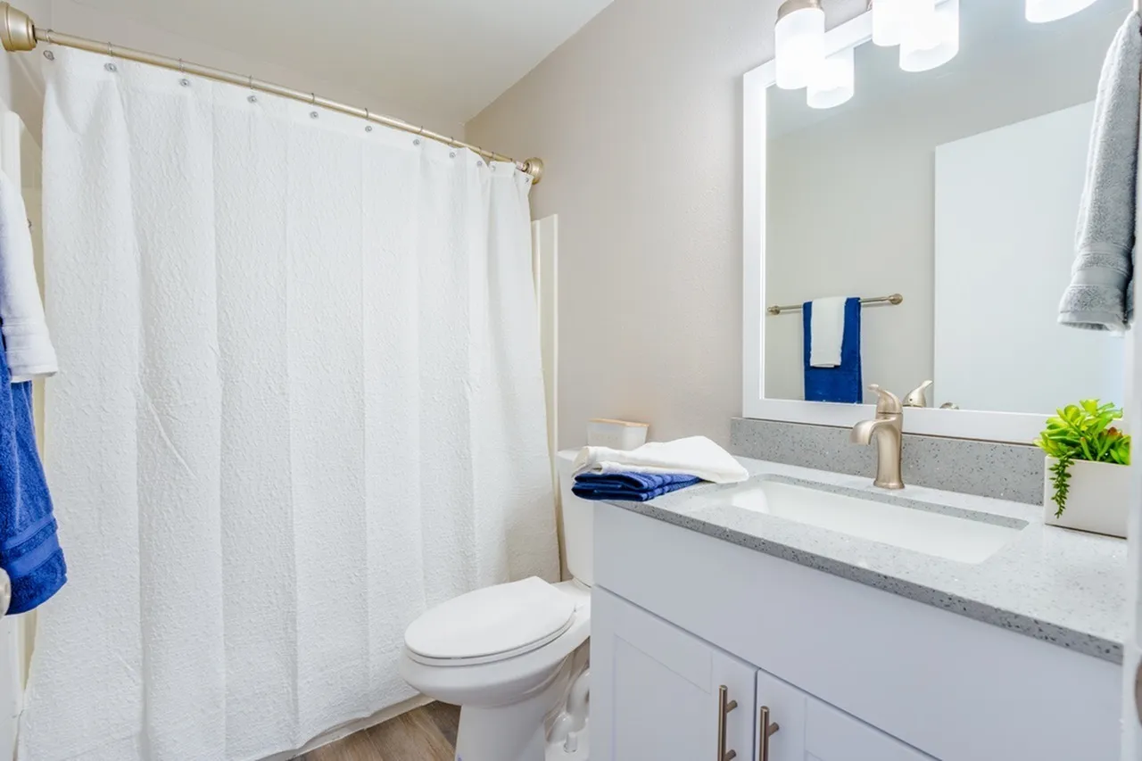 Bathroom, white vanity cabinetry, quartz countertop, framed mirror, chrome fixtures