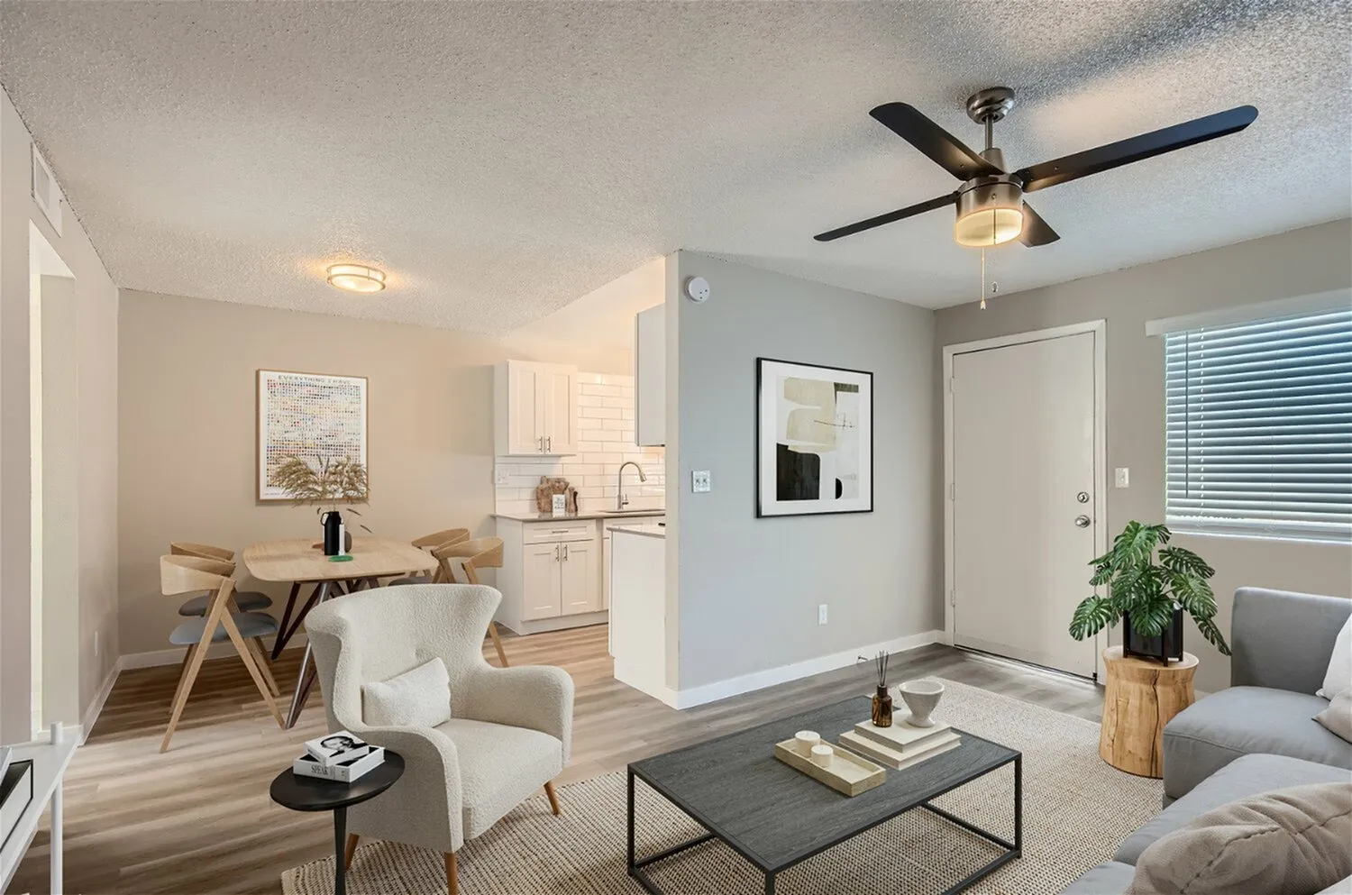 Studio apartment, wood-style plank flooring, ceiling fan, white cabinetry, gray upholstered furniture