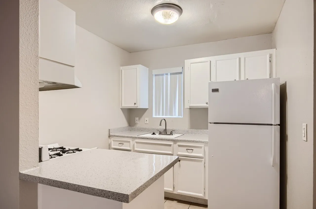 Kitchen, white shaker cabinetry, quartz countertops, stainless refrigerator, gas cooktop