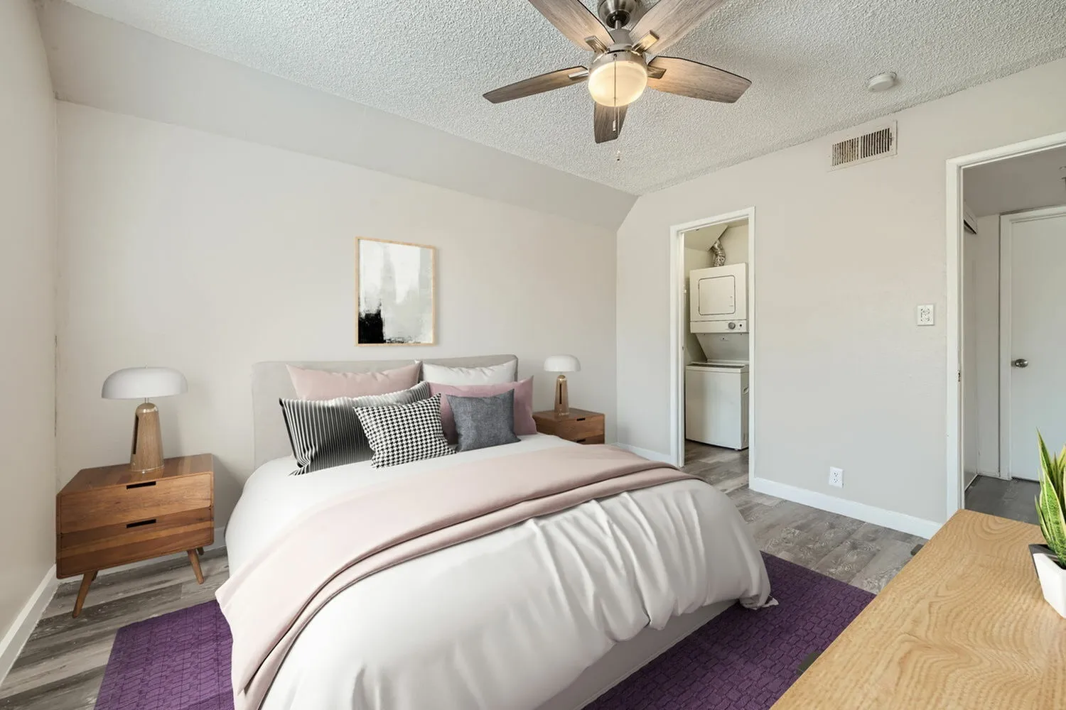 Primary bedroom, wood-style plank flooring, purple area rug, ceiling fan, ensuite bathroom visible