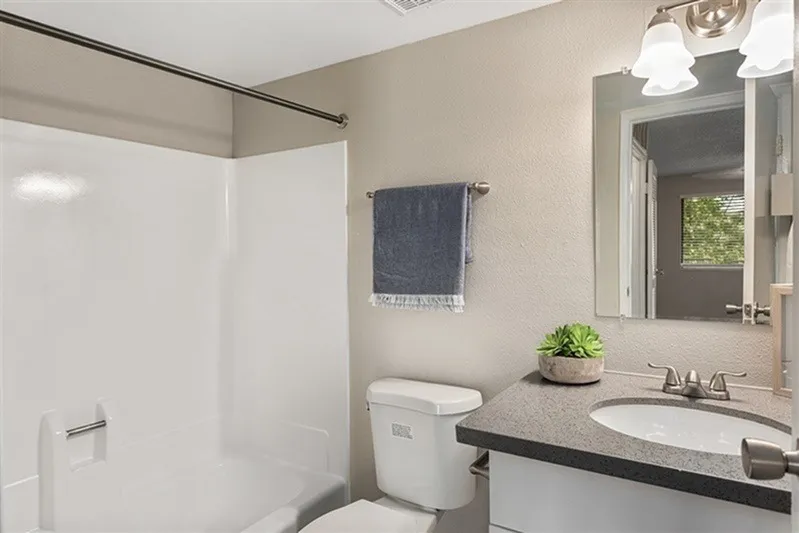 Bathroom, gray quartz countertops, white ceramic sink, chrome faucet, white shower surround