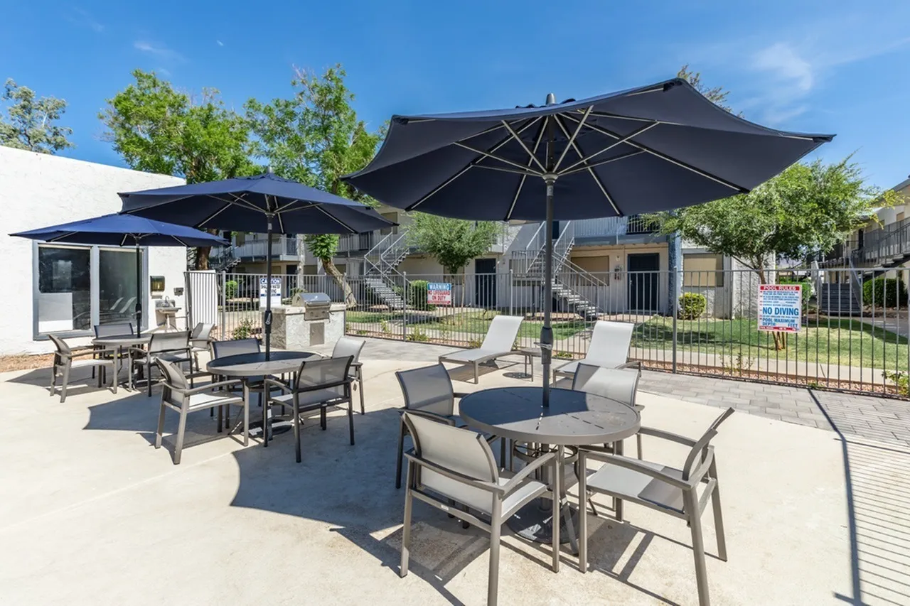 Patio with black umbrellas, dining tables, lounge chairs, fenced courtyard