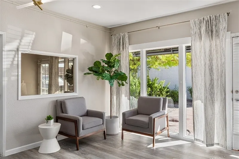Entryway, gray upholstered chairs, wood-style plank flooring, indoor plant, glass doors to patio