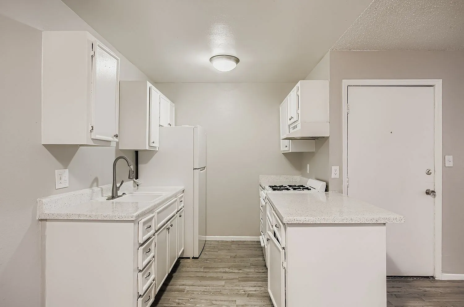 Kitchen, white shaker cabinetry, quartz countertops, stainless appliances, wood-style plank flooring