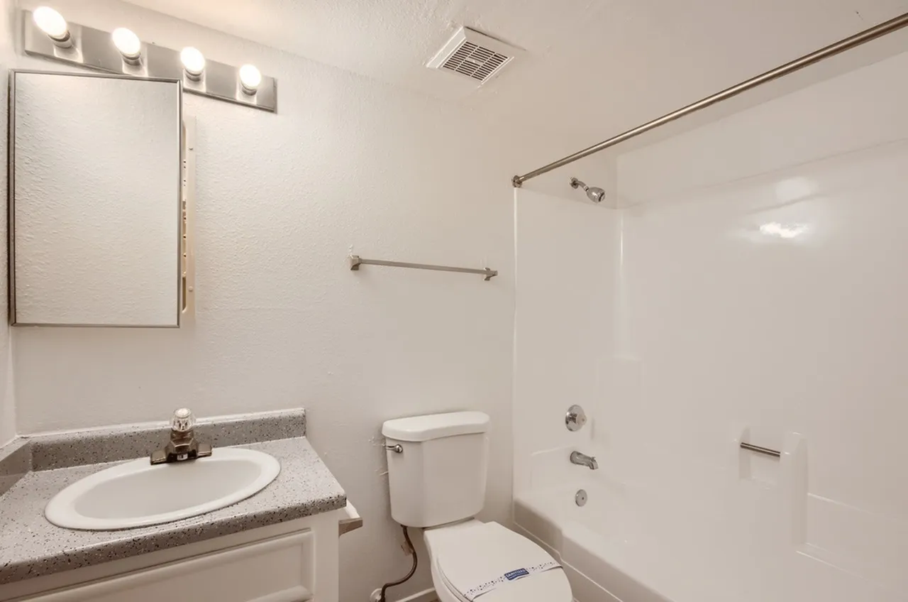 Bathroom, gray quartz countertop, round white sink, mirrored medicine cabinet, white tile shower enclosure