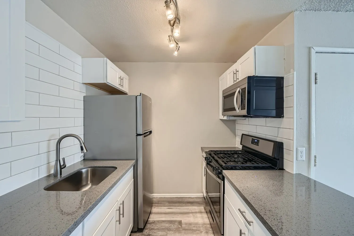 Kitchen, white shaker cabinetry, gray quartz countertops, stainless appliances, wood-style plank flooring