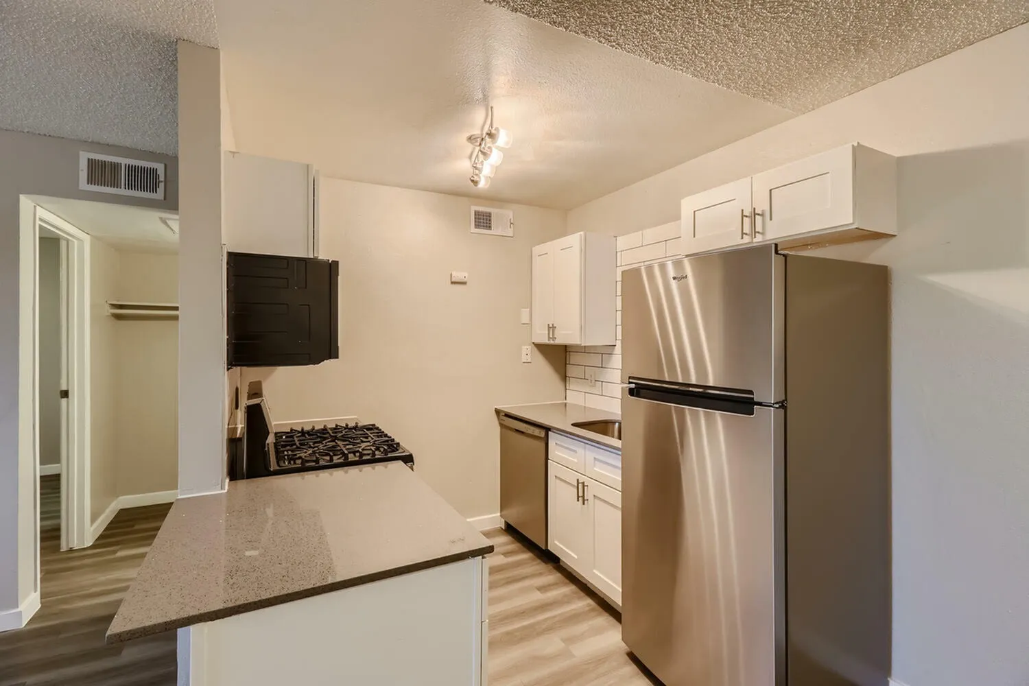 Kitchen, white shaker cabinetry, stainless steel appliances, wood-style plank flooring