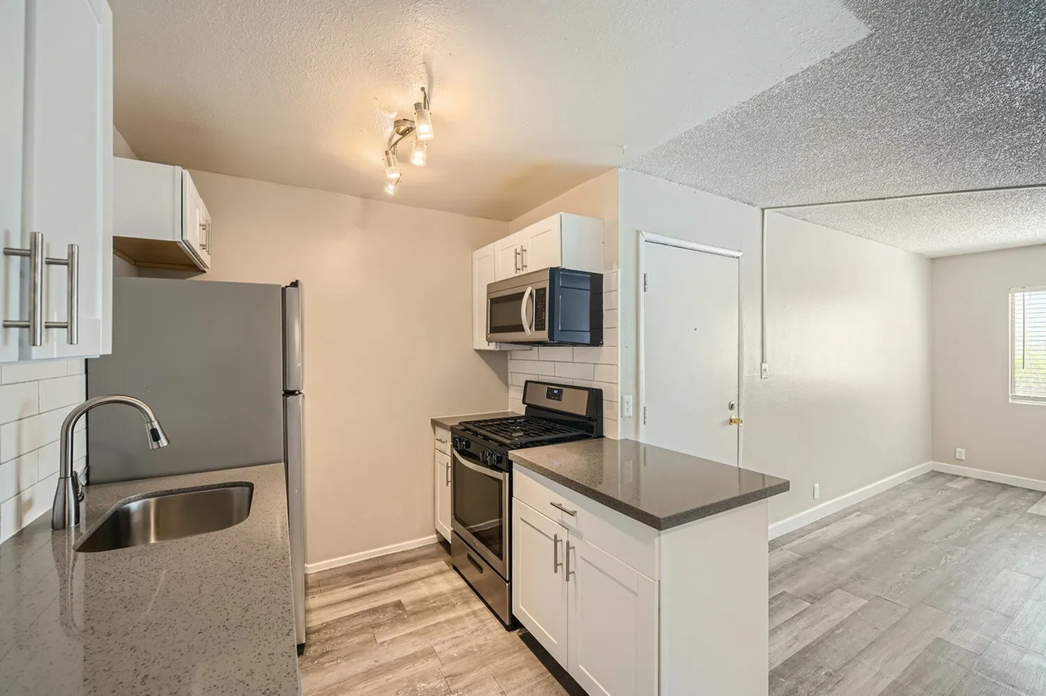 Kitchen, white shaker cabinetry, gray quartz countertops, stainless appliances, wood-style plank flooring