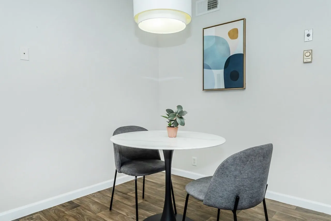 Meeting room, white oval table, gray upholstered chairs, wood-style plank flooring, pendant lighting
