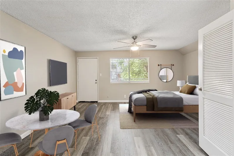 Studio bedroom, wood-style plank flooring, ceiling fan, round dining table