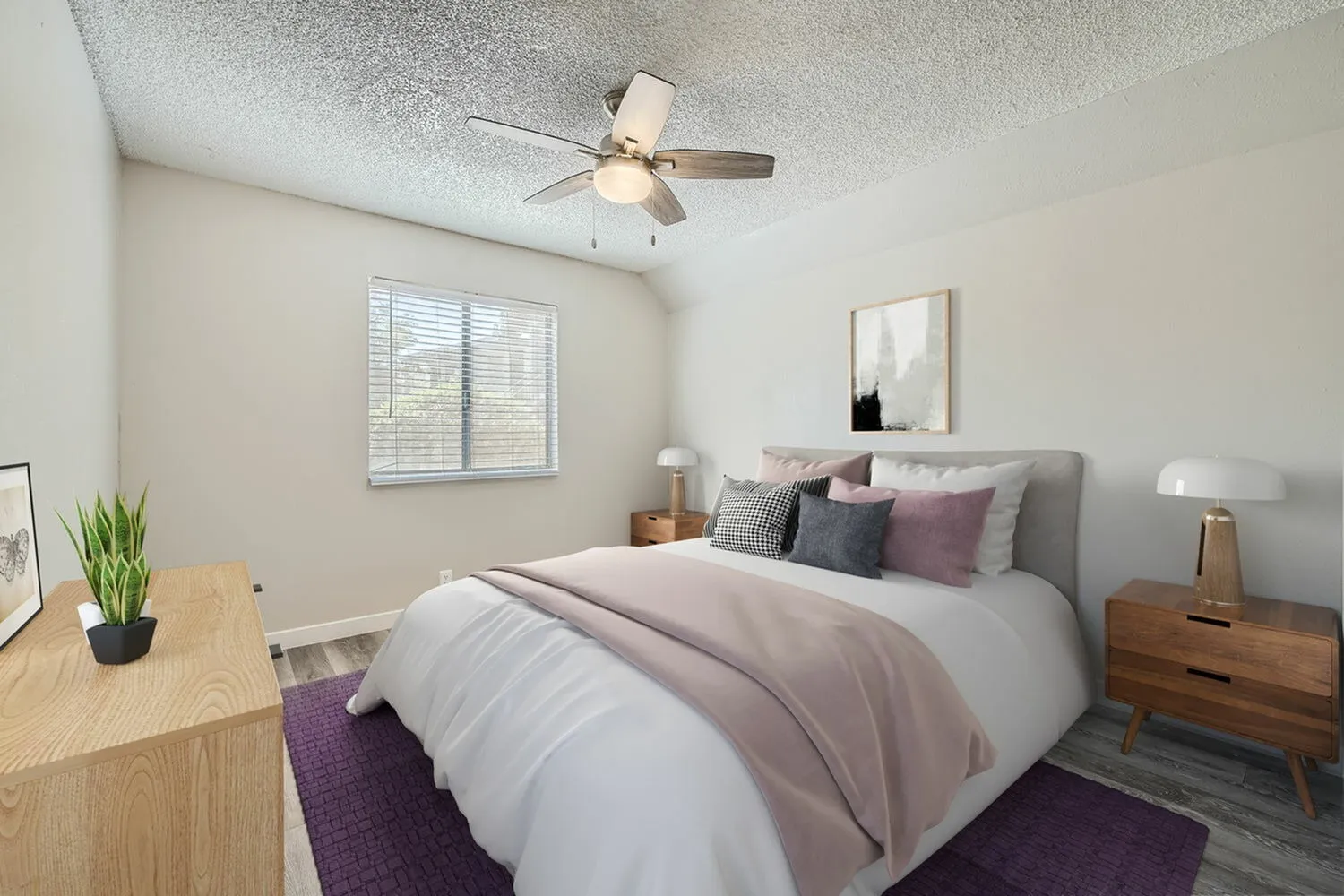 Primary bedroom, wood-style plank flooring, ceiling fan, gray upholstered bed with pillows