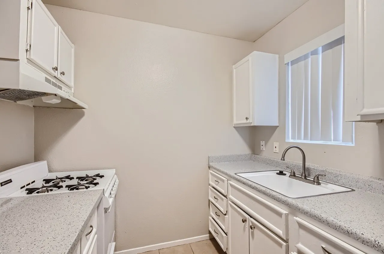 Kitchen, white shaker cabinetry, quartz countertops, gas range, undermount sink, vertical blinds