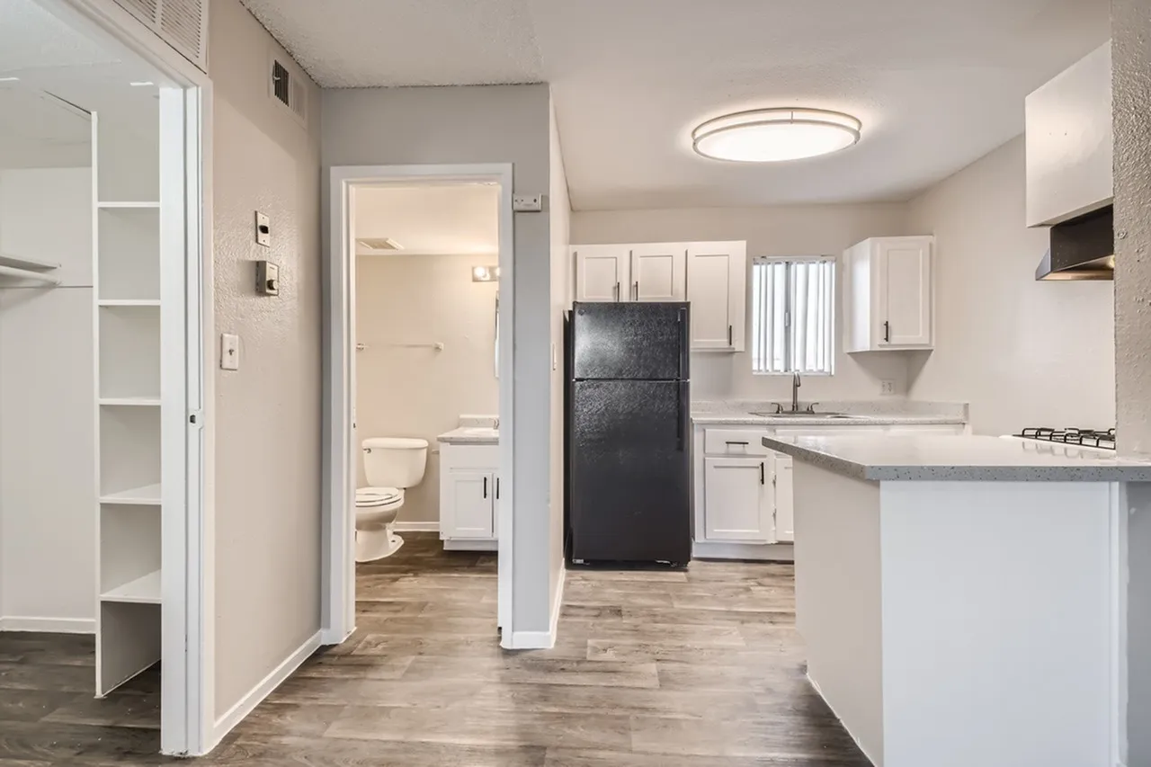 Kitchen and bathroom view, white shaker cabinetry, black refrigerator, wood-style plank flooring