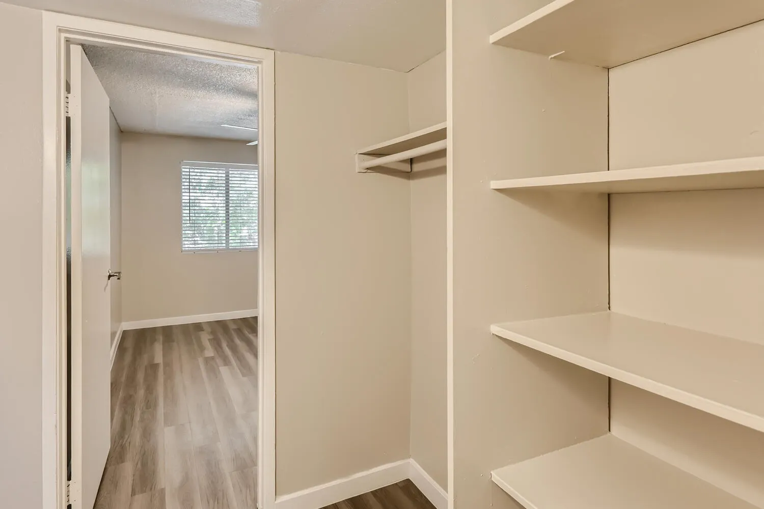 Walk-in closet, white shelving, wooden-style plank flooring, open storage