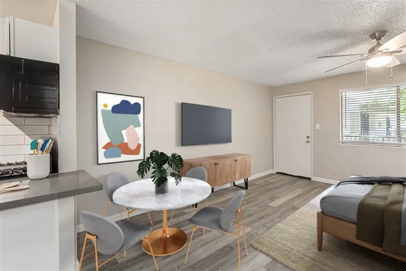 Studio apartment open living space with wood-style plank flooring, modern abstract wall art, ceiling fan, wood-look media console