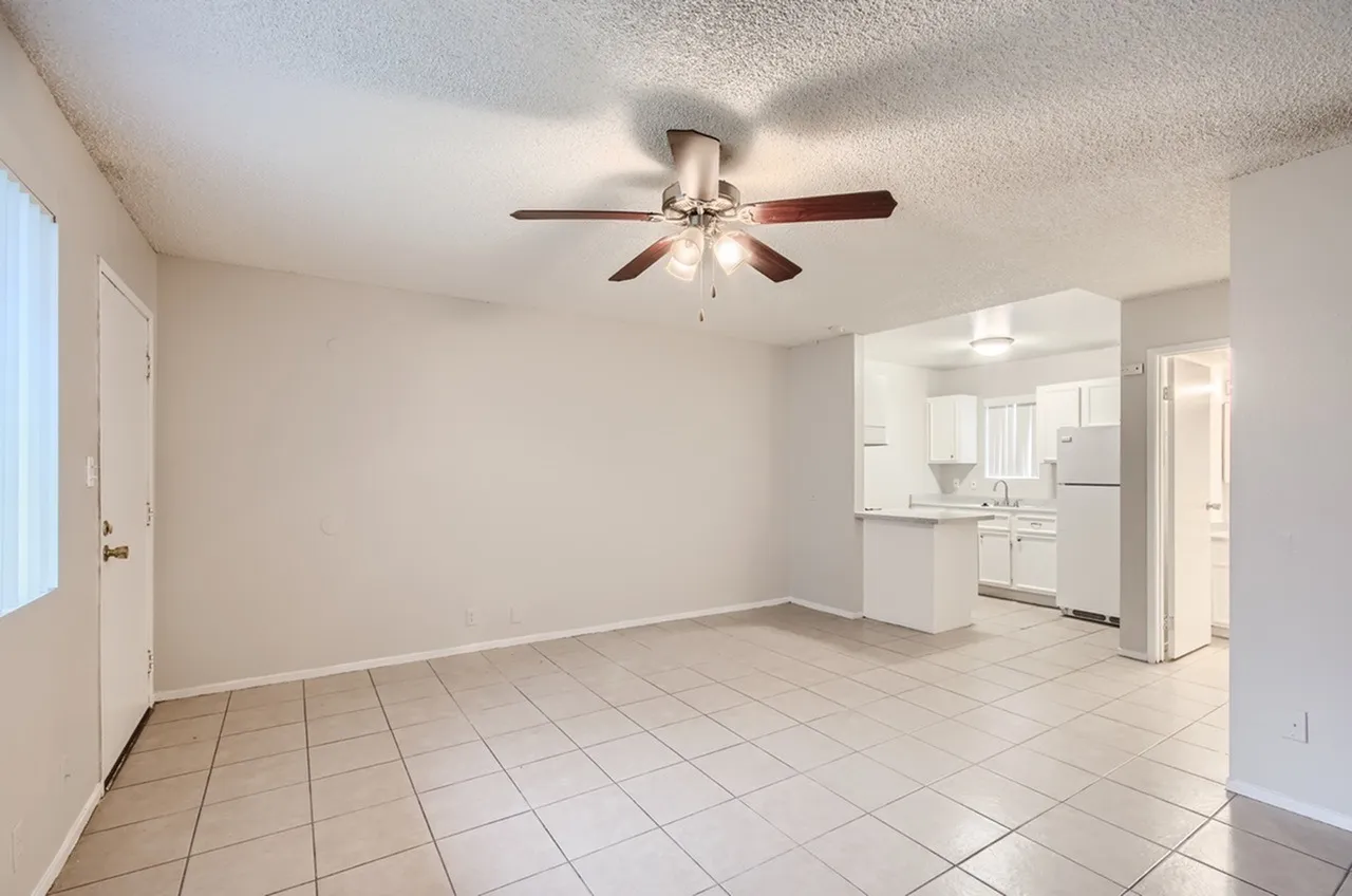 Living room with wood-style plank flooring, ceiling fan, open concept to kitchen with stainless appliances