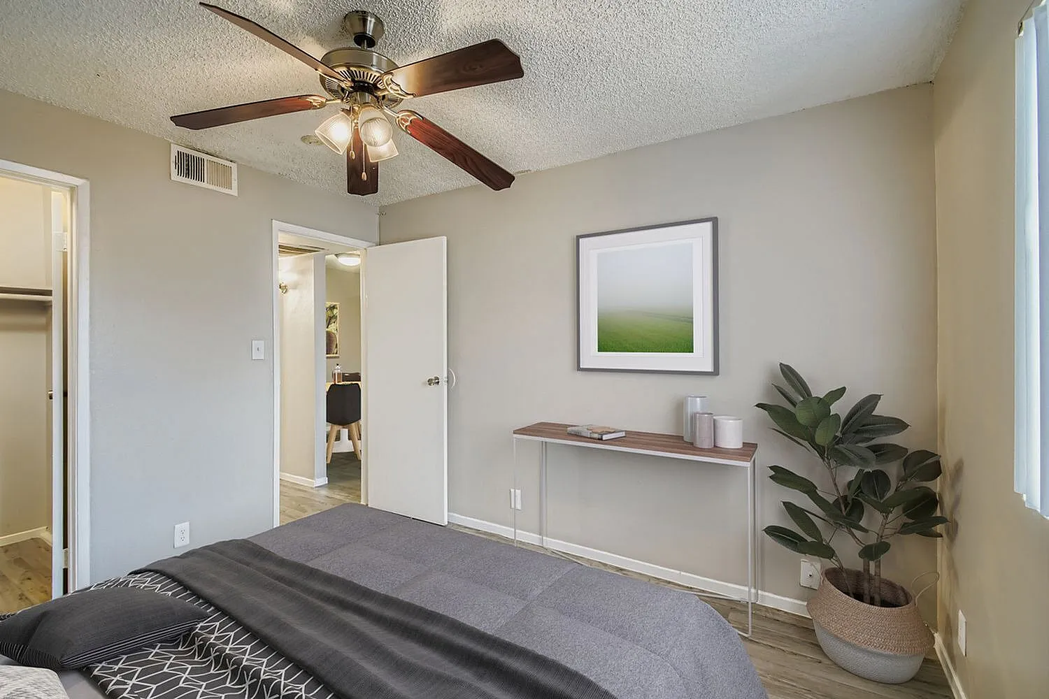 Primary bedroom, wood-style plank flooring, ceiling fan with light, potted plant