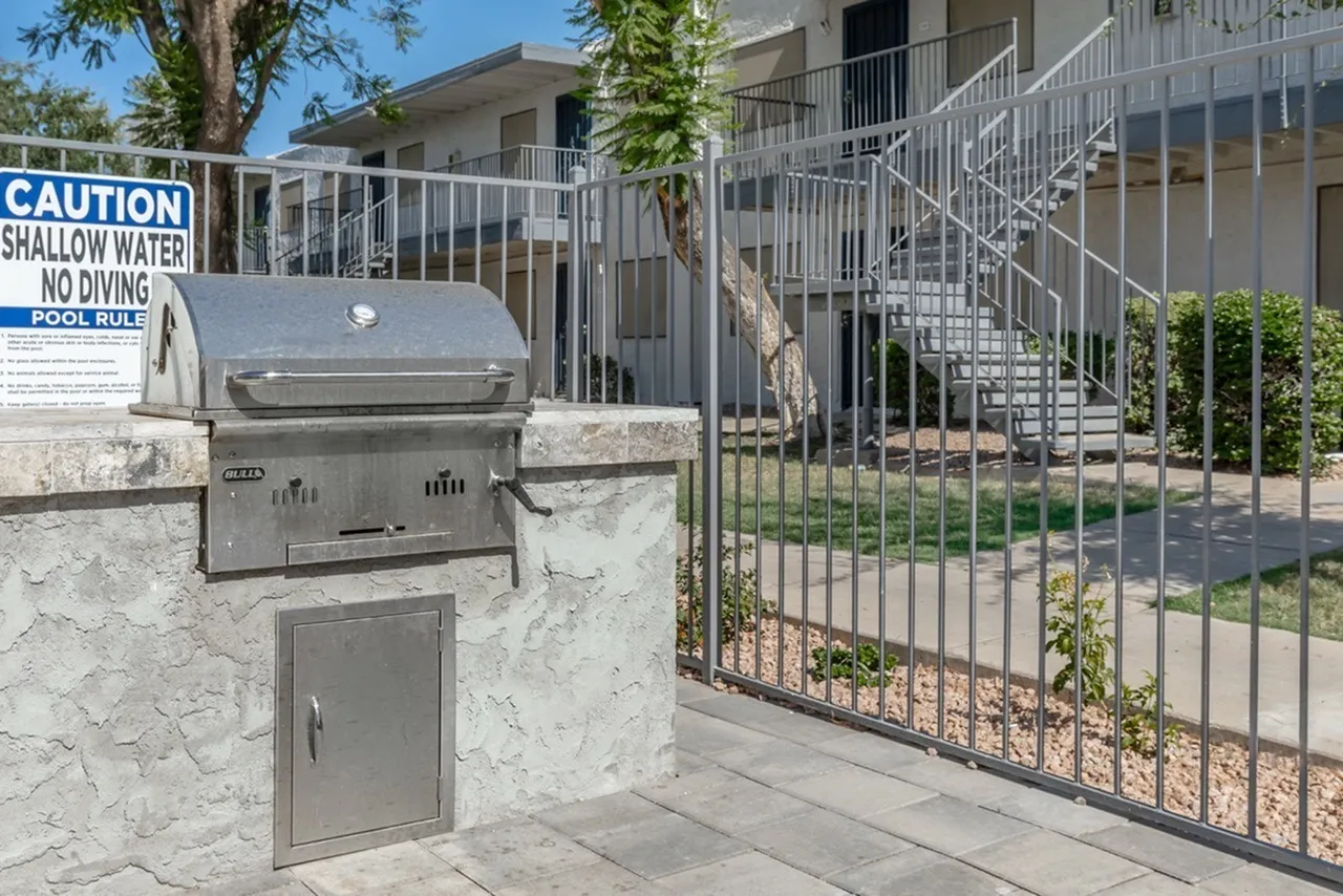 Built-in stainless grill, concrete patio, metal railing fence, shallow water caution sign