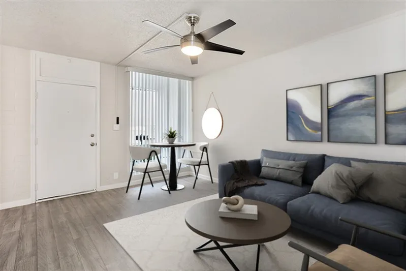 Living room, wood-style plank flooring, black ceiling fan, gray sofa, round coffee table